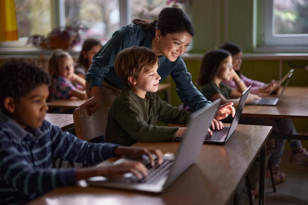Teacher over student looking at laptop screen